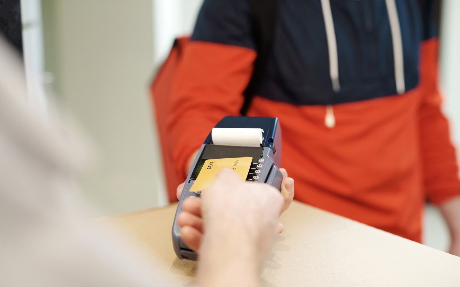 Tarjeta contactless acercándose a un terminal de pago en un comercio