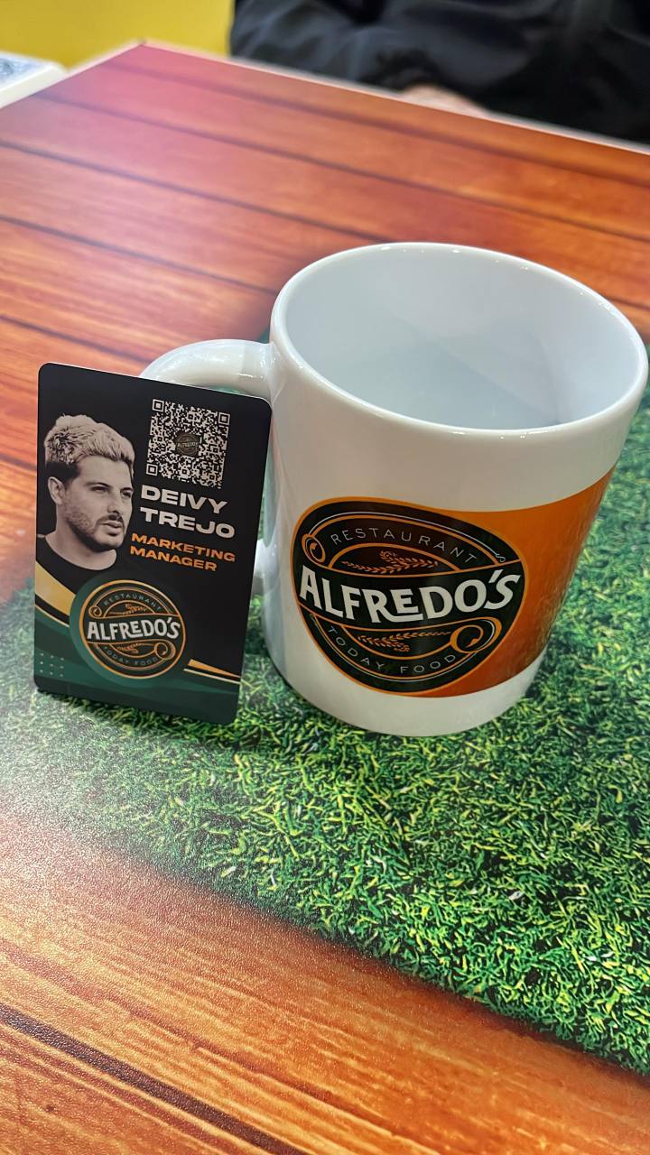 Tarjeta inteligente personalizada de Alfredo’s Restaurant junto a una taza corporativa